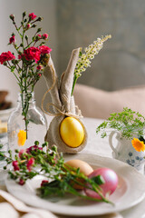 Happy Easter. Stylish easter eggs on a napkin with spring flowers on white wooden background. Table...