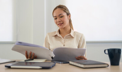 Fototapeta premium Serious businesswoman sitting in front of laptop computer at her workplace and reading financial reports..