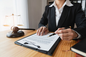 Asian female legal advisor or a lawyer using a pen to check business information and various details Business venture capital acknowledgment signing on paperwork at a desk in her office.