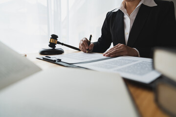 Lawyer, legal adviser, asian businesswoman looking at and writing down contract details business law Study and check the accuracy before signing and clarifying in the office.