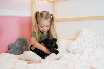 Caucasian little girl with a puppy. Child holding dog. Pet concept