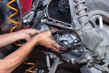 Motorcycle mechanic check the condition of Auto Transmission system or Clutch system of scooter at workshop. Repair and maintenance motorcycle concept.selective focus
