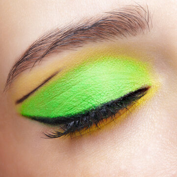 Closeup macro shot of closed human female eye. Girl with green and yellow eyes shadows