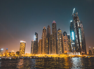 Obraz na płótnie Canvas Dubai Marina, harbour, cruise boat and canal promenade view at night, in Dubai, United Arab Emirates
