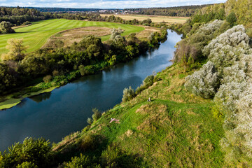 Aerial view of a landscape with a river flowing between fields and forest