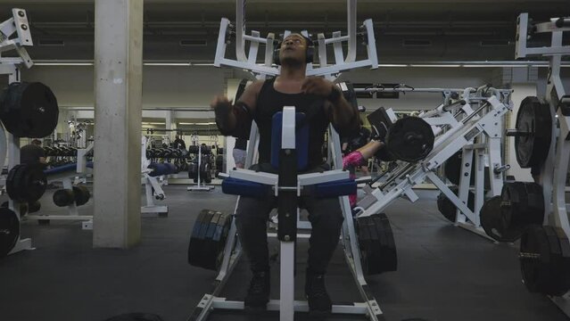Black Male Bodybuilder Strongman Athlete Is Lifting Black Weights with Left Hand On Sports Equipment in 4K