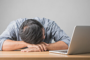 Workers bowed their heads or slept on the table with a laptop next to them. Overworked and tired concept.