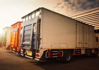 Cargo Container Trucks on The Parking Lot at Distribution Warehouse. Lifting Ramp Door. Lorry. Shipping Delivery Trucks. Freight Truck Logistics Cargo Transport	