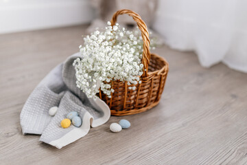 A basket of twigs with white flowers, a towel, blue, yellow, white eggs. Spring Background for Easter
