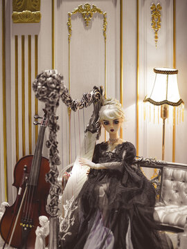 BKK - Mar 5, 2023: A photo of beautiful BJD doll is playing vintage harp in the luxury living room. Harpist lady doll in black lace dress is displayed at doll fair called Miss you doll Market Season6.