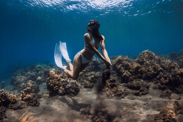 Woman freediver pose with sand in hands underwater in ocean