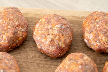 raw homemade meatballs on a massive board made of natural wood