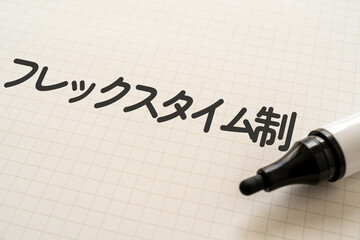 フレックスタイム制と書かれたノートとマーカー
