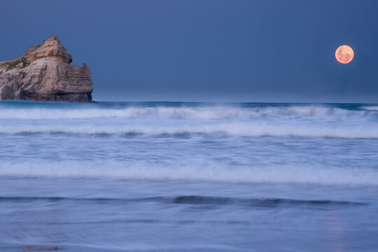 Full blue moon rising over the lagoon at sunset at the Castlepoint gap next to Castle rock