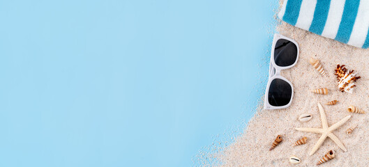 Top view with copy space of sand with starfish and sunglasses on blue background.