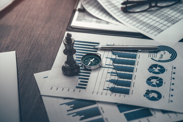 The King in chess pieces, compass and pen are placed on financial documents to signify being the...