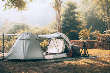 Gray tent on the grass in the forest The view behind is the mountain in the morning. Camping, Travel and holiday concept. - obrazy, fototapety, plakaty
