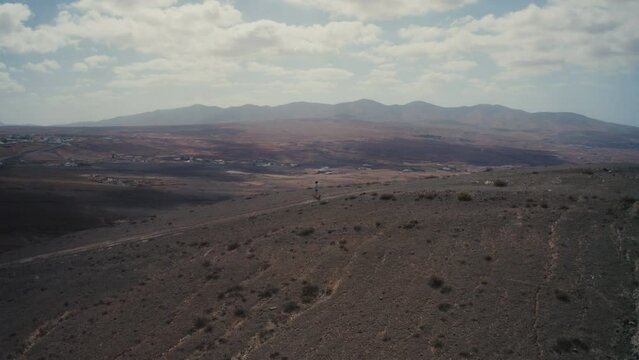 Drone shot of a girl walking on a mountain in fuerteventura