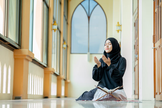 The image of an Asian Muslim woman in the Islamic religion in hijab in black color. She was praying in a beautiful mosque out of respect for God.