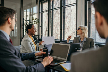 Panoramic view of female entrepreneurs talking to their colleagues about business reports of economy grow at a meeting in the office.