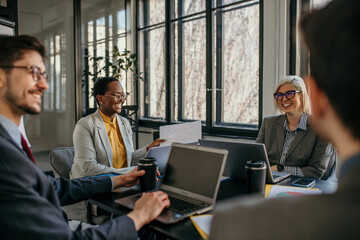 Panoramic view of female entrepreneurs talking to their colleagues about business reports of economy grow at a meeting in the office.