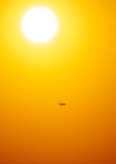 Silhouette of an airplane coming in for landing at sunset.