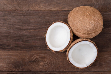 Brown coconut fruit and cut in half slice isolated on wooden table background. Top view, flat lay.