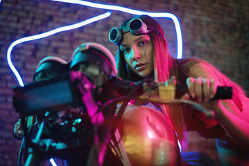 Naklejka na ściany i meble Girl a motorbiker near the cyberpunk motorcycle in the neon lights.