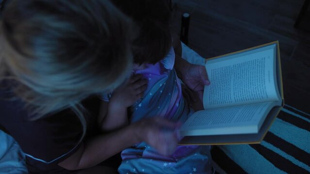 Mom reading a book to her daughter before bed