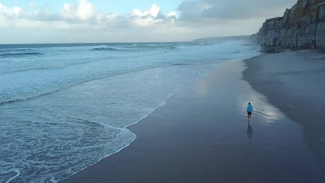 Aerial female beach jogging outdoors healthy lifestyle Portugal
