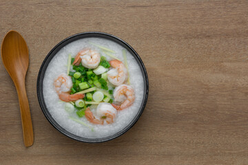 top view of rice porridge with shrimp in a ceramic bowl on wooden table. asian homemade style food concept.