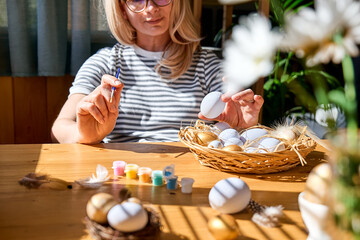 Hands of woman preparing easter decoration at home, painting colorful easter eggs and coloring egg...
