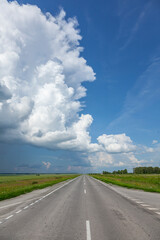 Road in the field under blue sky and clouds.
Beautiful view of an empty highway in Siberia in the countryside under a stormy sky full of clouds.