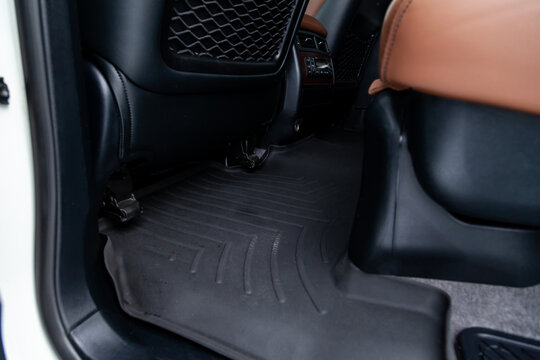 Clean car floor mats of black rubber under rear passenger seat in the workshop for the detailing vehicle dry cleaning. Auto service industry. Interior of sedan.