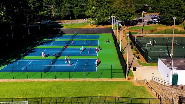 Aerial drone shot slowly rotating above athletes on a tennis court playing a pickle ball tournament in Atlanta, Georgia.