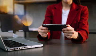 Businesswoman hand using smart phone laptop and tablet with social network diagram on desk as concept in morning light..