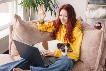 Smiling female student looking at laptop screen waving hand greeting tutor.