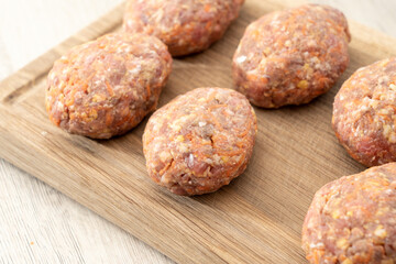 raw homemade meatballs on a massive board made of natural wood