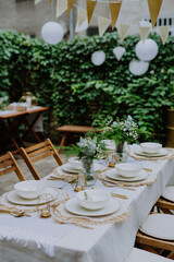 Festive wedding table setting with flowers at small reception in backyard in summer.