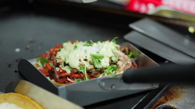 Adding avocado sauce to the bottom of a mulita - food truck series