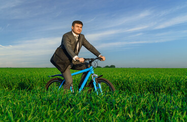 Fototapeta na wymiar a businessman rides a bicycle on a green grassy field, dressed in a business suit, beautiful nature in spring, freelance business concept