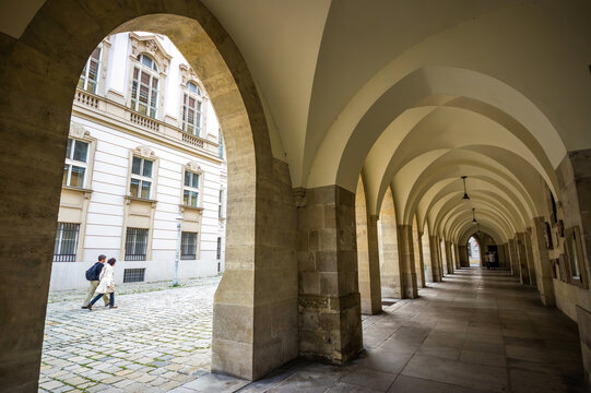 Covered alley with multiple arches and couple walking in Vienna, Austria