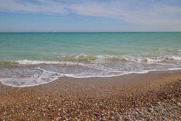 Blue sea, waves, sandy beach and pebbles