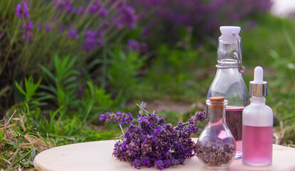 jars with lavender oil, lavender flowers, on the background of a lavender field.