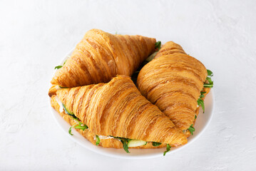 Fresh croissants sandwiches with salmon fish, cream cheese and arugula in plate.
