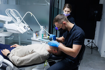 A man at an appointment with an orthodontist, orthodontic treatment of teeth. Modern medical orthodontic office. Dental care.