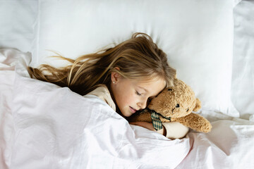 Candid lifestyle portrait of caucasian child eight years old in pajamas sleeping in bed at cozy...