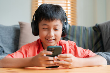 Portrait. Asian boy playing online game on smart phone with headphones . - 578248360