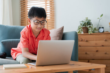 Asian little boy using laptop computer, typing, at home - 578248372