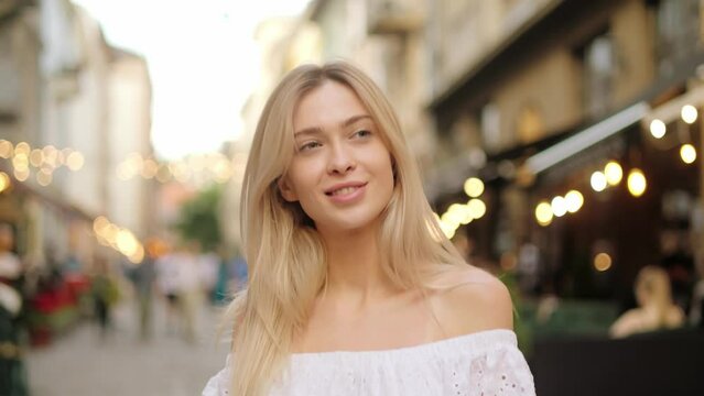 Beautiful woman with gorgeous golden hair.  Fun happy young girl walks down the city street in a good mood, smiling